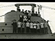 HMS Talisman. Close up of conning tower and bridge with crew members including Lt Cdr M. Willmott, displaying their Jolly Roger. (Royal Navy Submarine Museum)